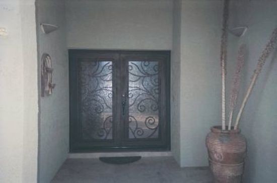 Inspiration for a large rustic one-story adobe beige and concrete floor front door remodel in Phoenix with beige walls and a black front door