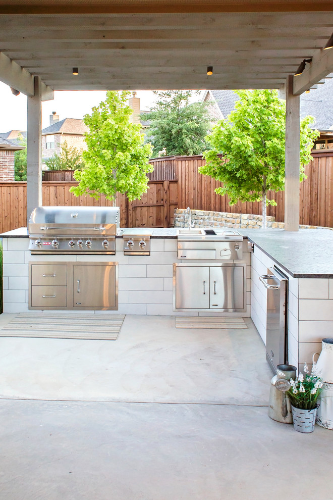 This is an example of a large eclectic backyard patio in Dallas with an outdoor kitchen, concrete pavers and a pergola.