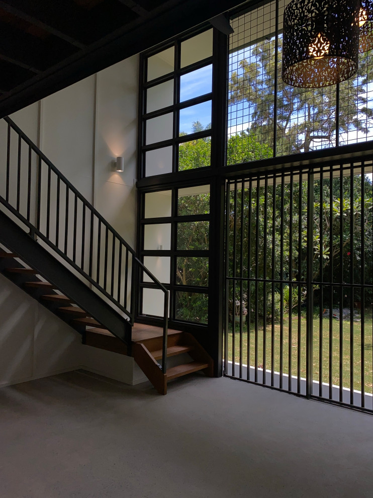 Идея дизайна: лестница среднего размера с деревянными ступенями, металлическими перилами и панелями на части стены без подступенок