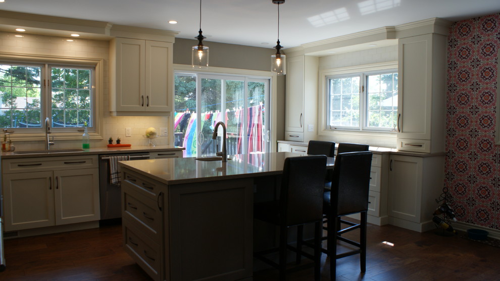 Example of a large transitional l-shaped eat-in kitchen design in Toronto with an undermount sink, shaker cabinets, white cabinets, quartz countertops, white backsplash, subway tile backsplash, stainless steel appliances and an island