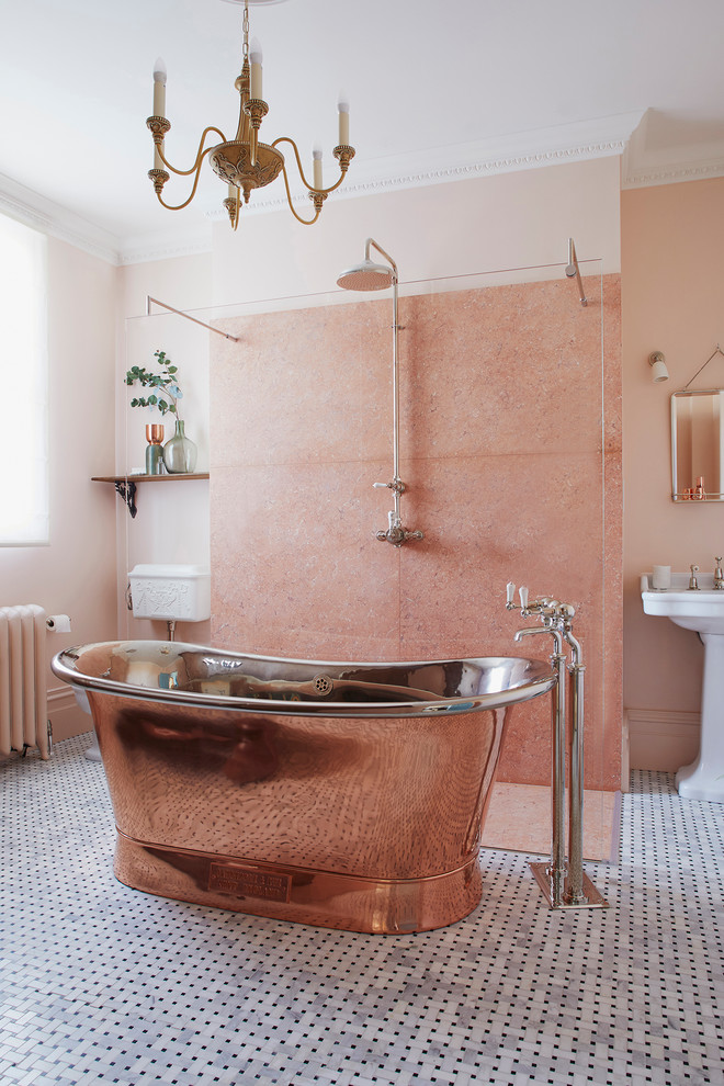 Large traditional kids bathroom in London with furniture-like cabinets, dark wood cabinets, a freestanding tub, an open shower, a two-piece toilet, pink tile, marble, pink walls, mosaic tile floors, a pedestal sink, black floor and an open shower.