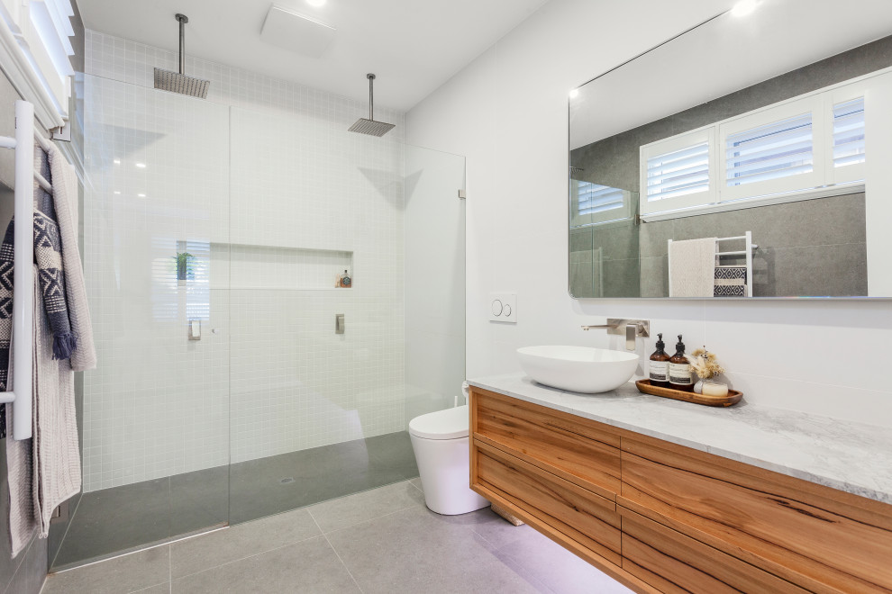 Inredning av ett modernt mellanstort badrum, med en dubbeldusch, en vägghängd toalettstol, marmorkakel, vita väggar, klinkergolv i keramik, marmorbänkskiva, grått golv och dusch med gångjärnsdörr