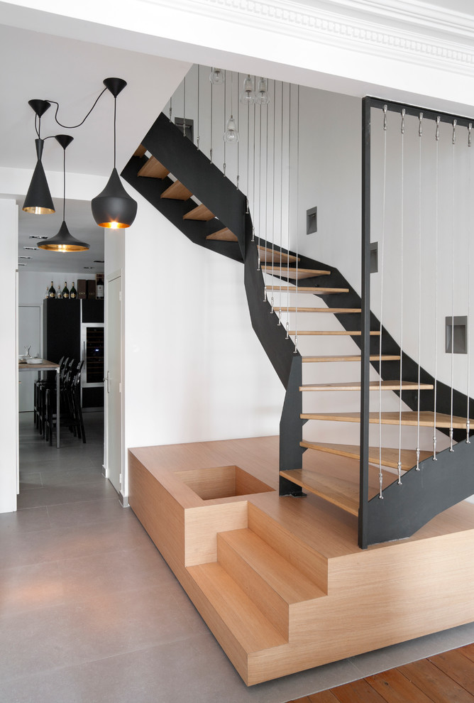 Photo of a large contemporary wood curved staircase in Paris with open risers.