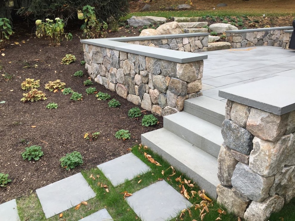 This is an example of a mid-sized transitional side yard patio in Boston with natural stone pavers and no cover.