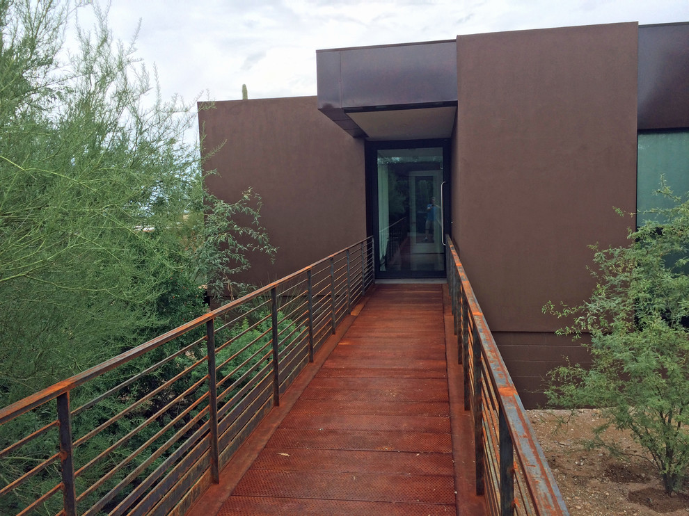 This is an example of a large modern one-storey stucco brown exterior in Phoenix with a flat roof.