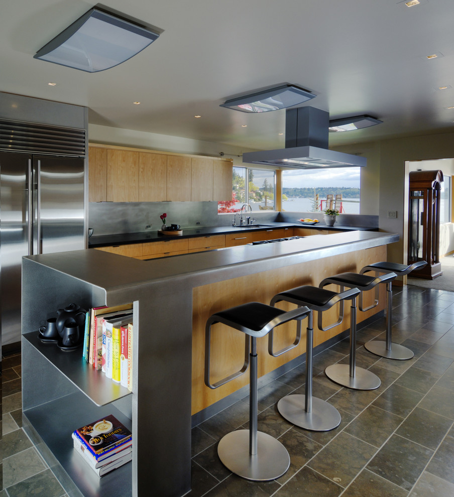 This is an example of a contemporary u-shaped eat-in kitchen in Seattle with stainless steel appliances, an undermount sink, flat-panel cabinets, medium wood cabinets, grey splashback and metal splashback.