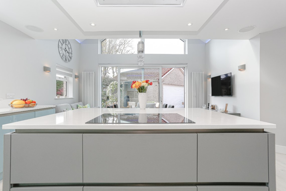 Foto di una cucina minimalista di medie dimensioni con ante lisce, ante blu, elettrodomestici neri, pavimento grigio, top bianco e lavello integrato