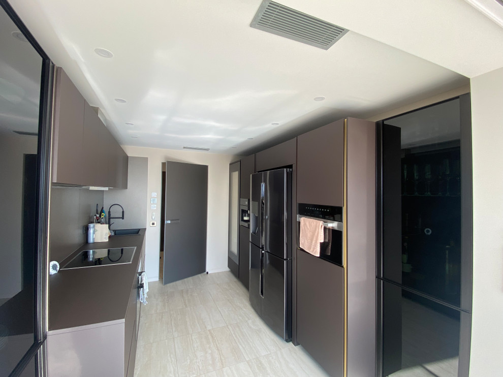 На фото: отдельная, параллельная кухня среднего размера, со шкафом над холодильником в современном стиле с плоскими фасадами, столешницей из ламината, бежевым полом и коричневой столешницей без острова с