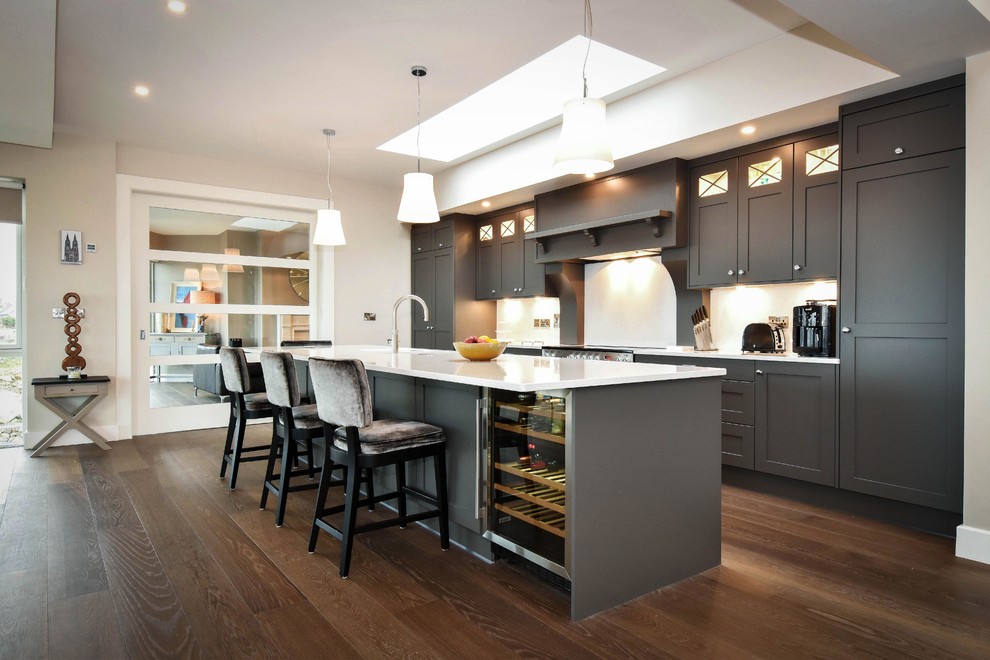 Design ideas for a mid-sized transitional single-wall kitchen in Other with recessed-panel cabinets, grey cabinets, quartzite benchtops, white splashback, dark hardwood floors, with island, brown floor and white benchtop.