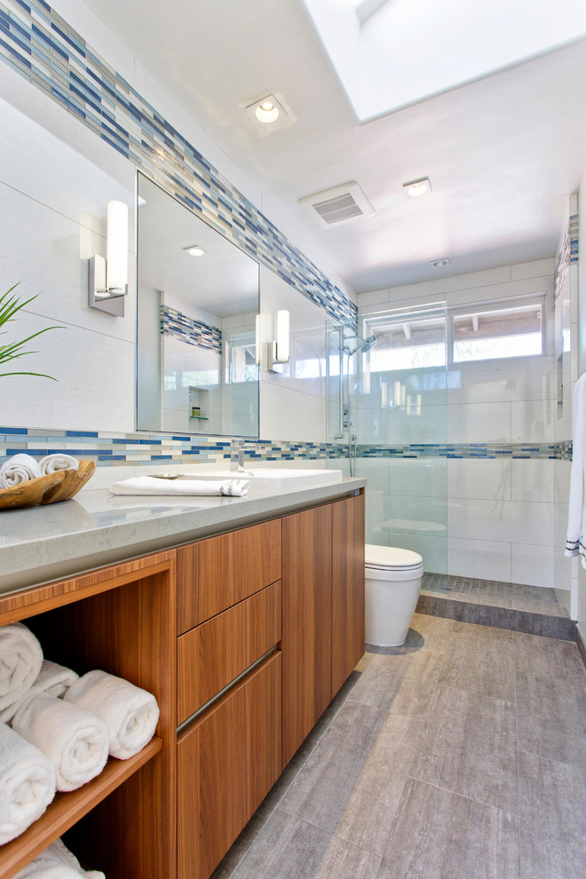 Photo of a contemporary bathroom in Denver with a drop-in sink, flat-panel cabinets, medium wood cabinets, quartzite benchtops, an alcove shower, white tile, porcelain tile, porcelain floors and grey benchtops.