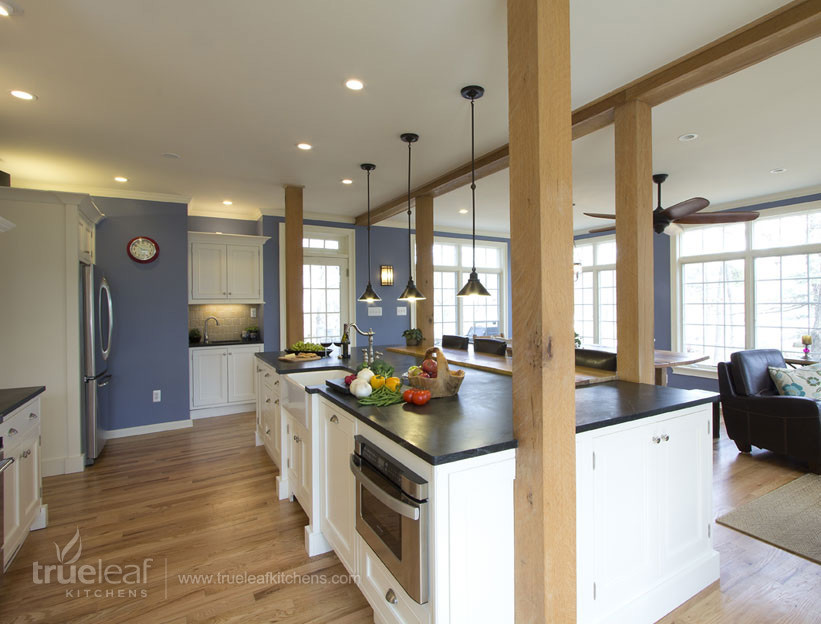This is an example of a transitional eat-in kitchen in New York with a farmhouse sink, beaded inset cabinets, white cabinets, soapstone benchtops, stainless steel appliances, light hardwood floors and with island.