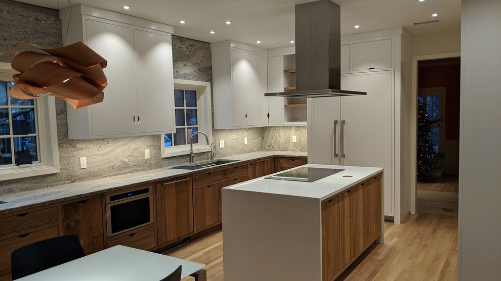 This is an example of a mid-sized contemporary galley separate kitchen in Dallas with a triple-bowl sink, beaded inset cabinets, white cabinets, granite benchtops, grey splashback, stone slab splashback, stainless steel appliances, light hardwood floors, with island, brown floor and grey benchtop.