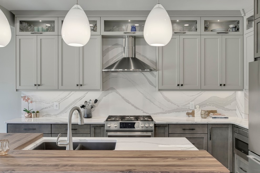 Large transitional u-shaped dark wood floor and brown floor eat-in kitchen photo in Calgary with an undermount sink, recessed-panel cabinets, gray cabinets, quartzite countertops, white backsplash, stone slab backsplash, stainless steel appliances, an island and white countertops