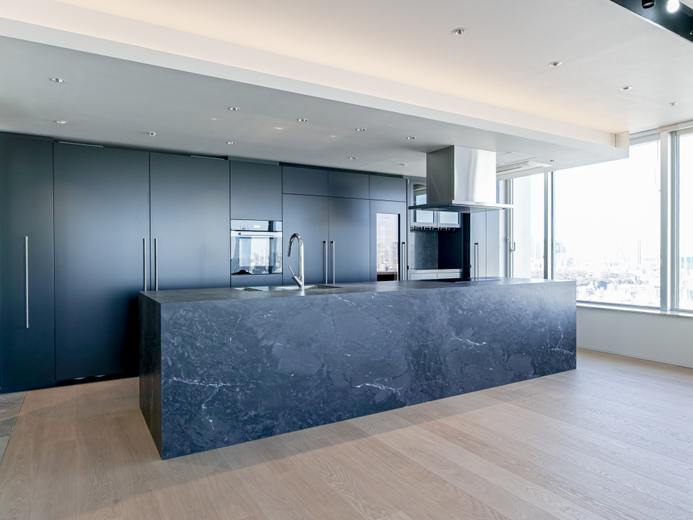 Diseño de cocina moderna abierta con puertas de armario grises, encimera de azulejos, una isla y encimeras negras