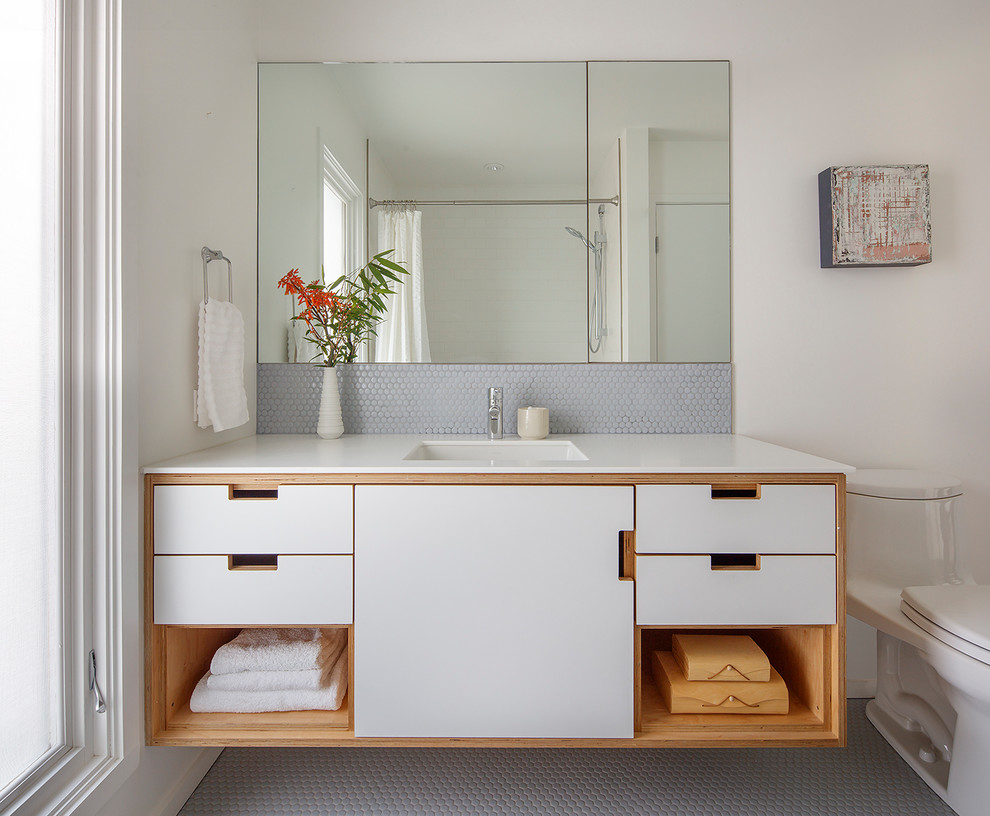 Photo of a large midcentury master bathroom in San Francisco with white cabinets, a one-piece toilet, white walls, a freestanding tub, an alcove shower, blue tile, subway tile, medium hardwood floors, a vessel sink, solid surface benchtops, brown floor, a hinged shower door and flat-panel cabinets.