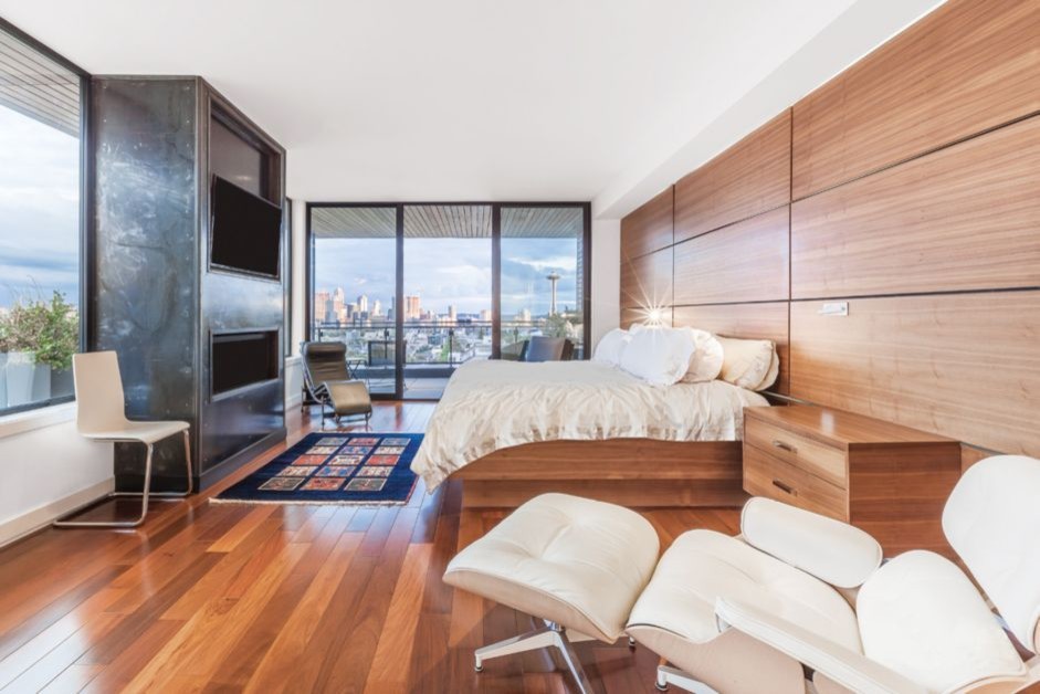 Large modern master bedroom in Seattle with brown walls, medium hardwood floors, a ribbon fireplace, a metal fireplace surround and brown floor.