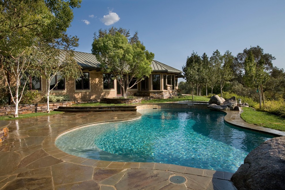Design ideas for a traditional backyard custom-shaped pool in Sacramento with natural stone pavers.