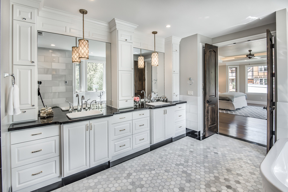 Photo of a transitional bathroom in Portland with raised-panel cabinets, white cabinets, white tile, grey walls, a drop-in sink, white floor and black benchtops.
