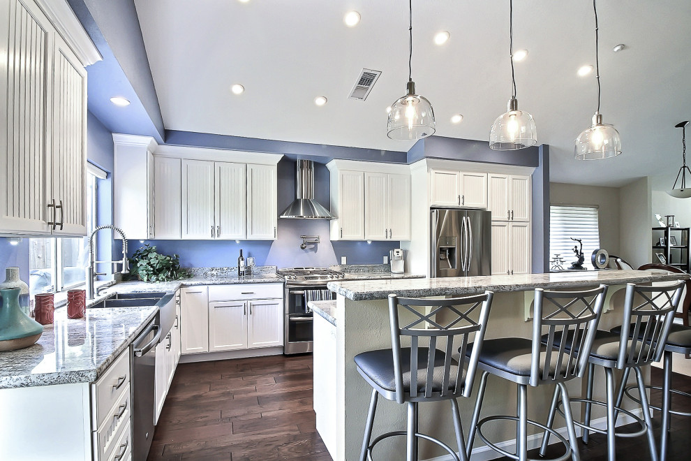 Große Moderne Wohnküche mit Unterbauwaschbecken, weißen Schränken, Küchenrückwand in Blau, Küchengeräten aus Edelstahl, braunem Boden und grauer Arbeitsplatte in San Francisco