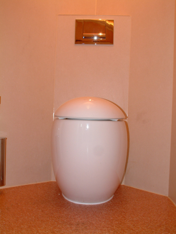 Inredning av ett klassiskt stort beige beige toalett, med en vägghängd toalettstol, brun kakel, glaskakel, beige väggar, linoleumgolv, ett fristående handfat, bänkskiva i glas och orange golv