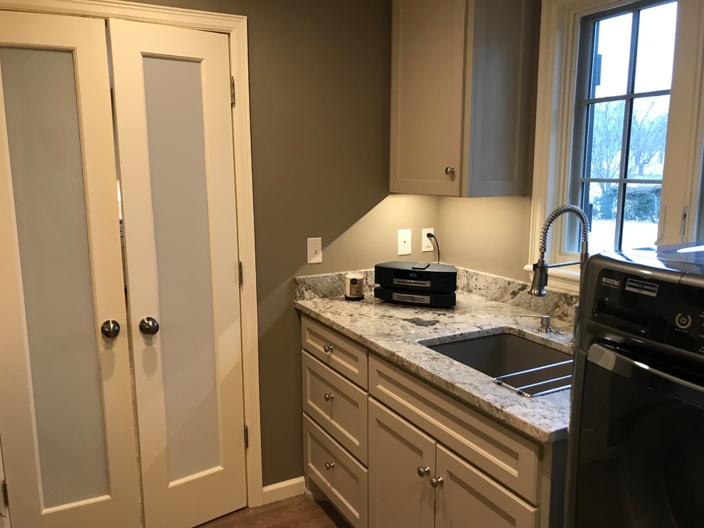 Inspiration for a large transitional galley utility room in Other with an undermount sink, shaker cabinets, grey cabinets, granite benchtops, light hardwood floors, a side-by-side washer and dryer, grey floor and grey walls.