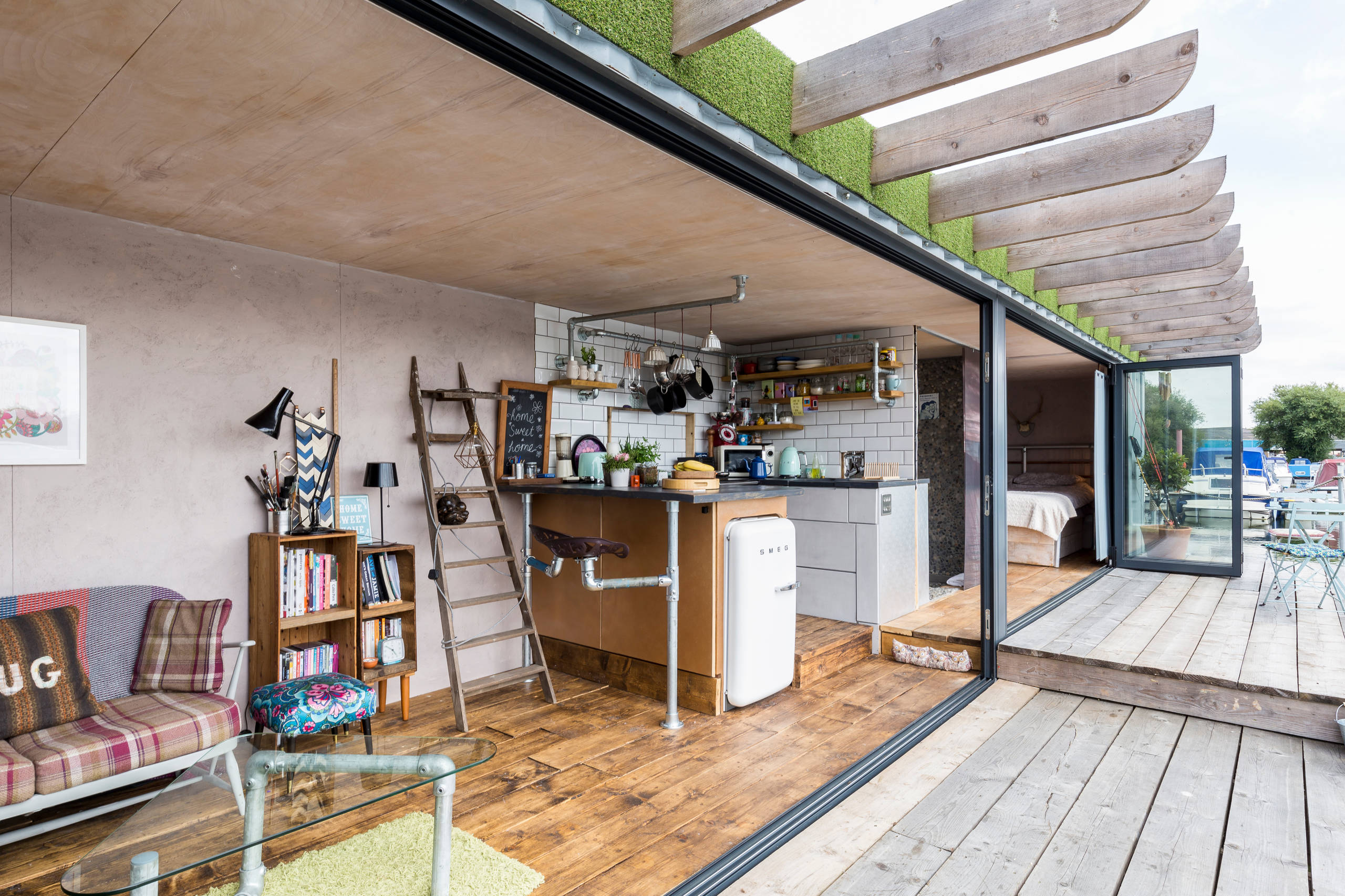 A person meditating on the deck of a shipping container home, overlooking a peaceful garden.