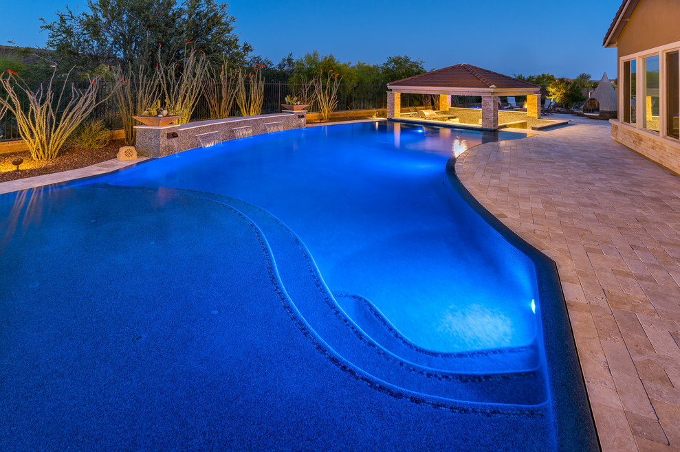 Large backyard stone and custom-shaped hot tub photo in Phoenix