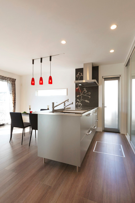 Mid-sized modern single-wall open plan kitchen in Other with an integrated sink, stainless steel cabinets, stainless steel benchtops, black splashback, mosaic tile splashback, black appliances, plywood floors, a peninsula and grey floor.