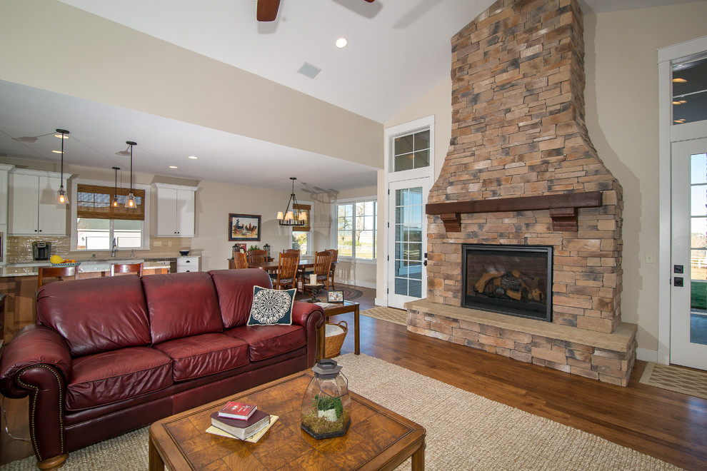 This is an example of a large arts and crafts open concept living room in Denver with beige walls, medium hardwood floors, a standard fireplace, a stone fireplace surround and brown floor.