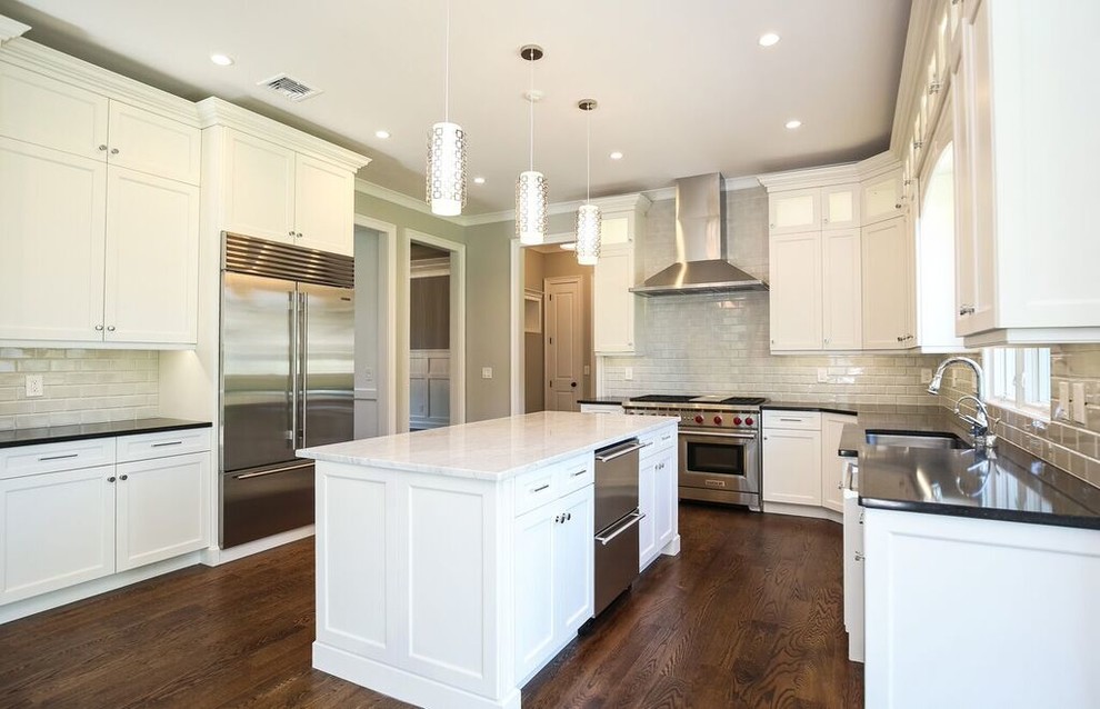 Photo of a mid-sized transitional l-shaped eat-in kitchen in New York with white cabinets, marble benchtops, stainless steel appliances, with island, ceramic splashback, dark hardwood floors, an undermount sink, recessed-panel cabinets and white splashback.
