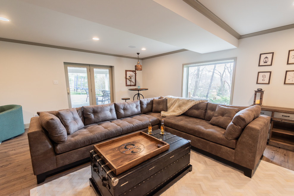 This is an example of a large country walk-out basement in Philadelphia with white walls, laminate floors, a corner fireplace, a stone fireplace surround and brown floor.