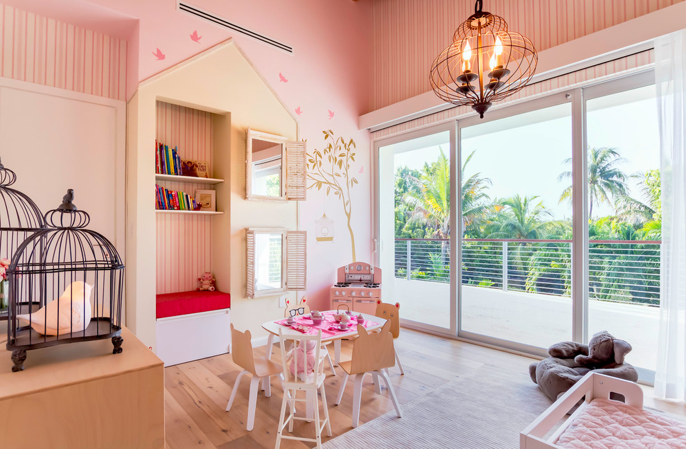 This is an example of a large transitional kids' room for girls in Miami with pink walls, light hardwood floors and beige floor.