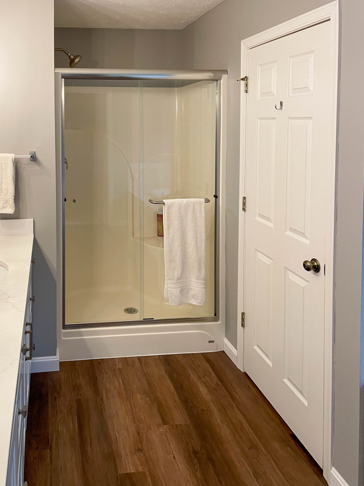 Klassisk inredning av ett mellanstort vit vitt en-suite badrum, med släta luckor, vita skåp, en dusch i en alkov, grå väggar, mellanmörkt trägolv, ett undermonterad handfat, bänkskiva i kvarts och dusch med skjutdörr