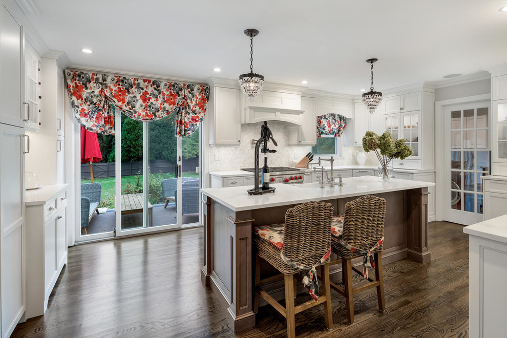 Inspiration for a mid-sized transitional u-shaped medium tone wood floor enclosed kitchen remodel with a farmhouse sink, recessed-panel cabinets, white cabinets, quartz countertops, white backsplash, marble backsplash, paneled appliances and an island