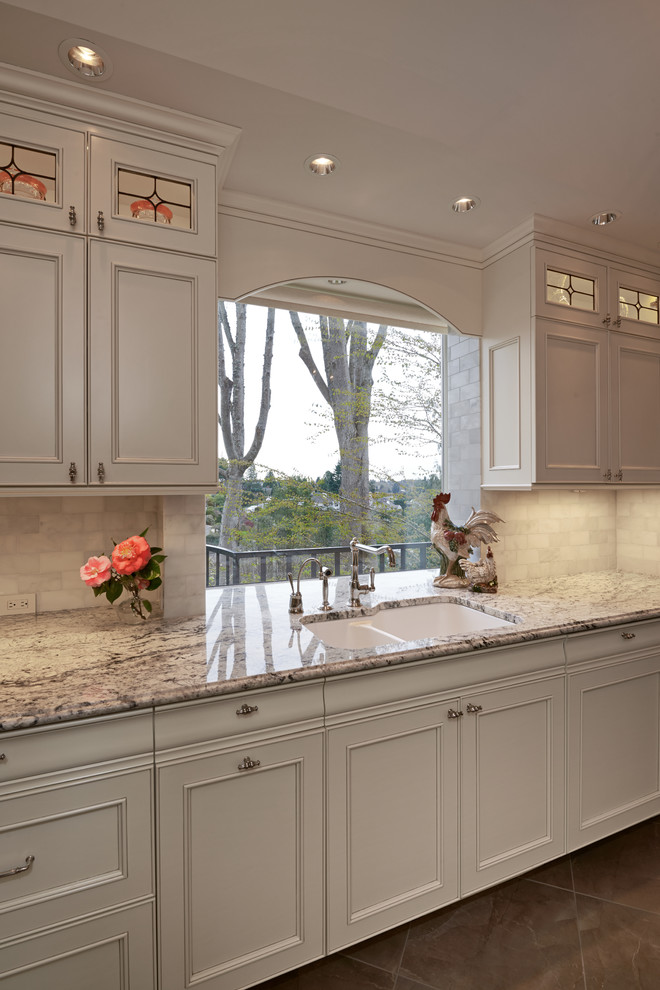 Small traditional galley open plan kitchen in Seattle with an undermount sink, beaded inset cabinets, white cabinets, granite benchtops, white splashback, stone tile splashback, panelled appliances, porcelain floors and no island.