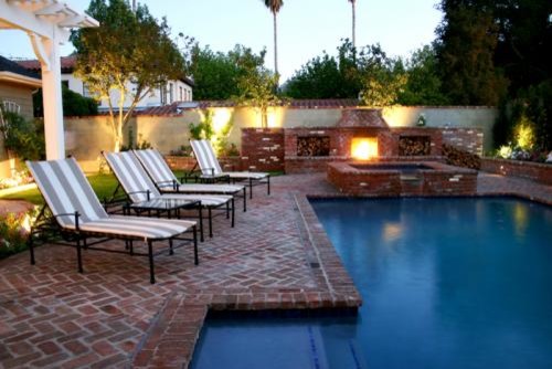 Midcentury backyard l-shaped aboveground pool in Los Angeles with a hot tub and brick pavers.
