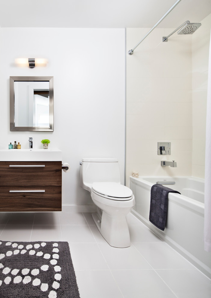 Mid-sized industrial bathroom in Toronto with a wall-mount sink, flat-panel cabinets, dark wood cabinets, an alcove tub, a shower/bathtub combo, a one-piece toilet, beige tile, white walls and ceramic floors.