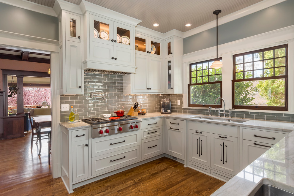 Mid-sized transitional u-shaped medium tone wood floor and brown floor enclosed kitchen photo in Seattle with an undermount sink, beaded inset cabinets, gray cabinets, quartzite countertops, gray backsplash, ceramic backsplash, paneled appliances and a peninsula