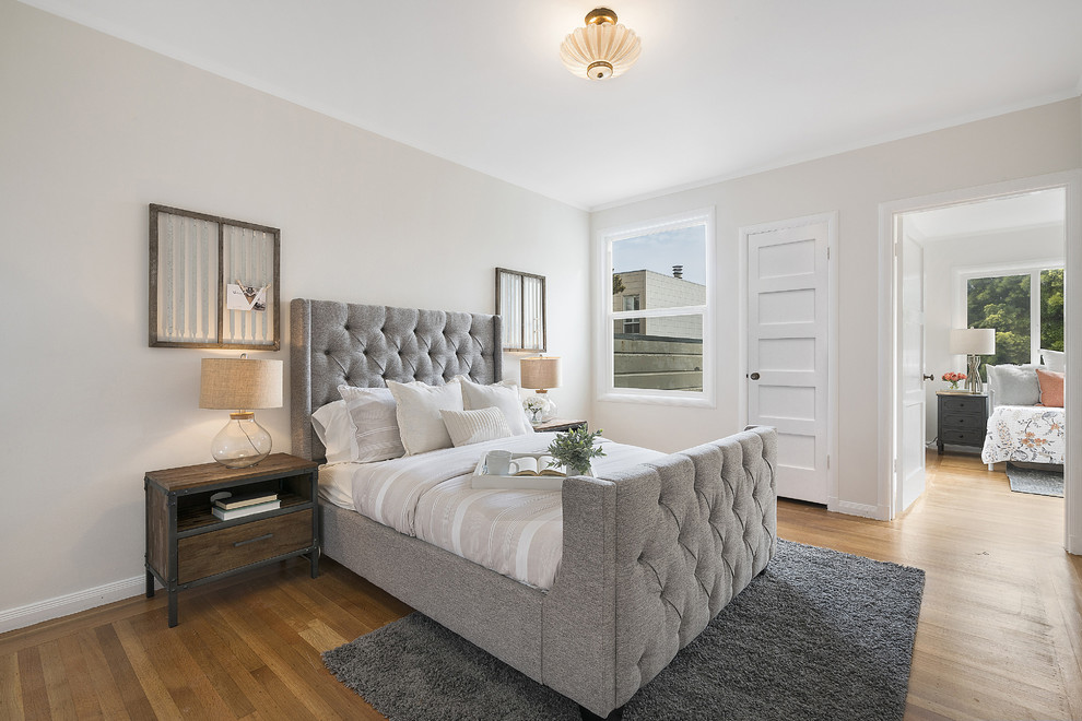 This is an example of a transitional master bedroom in Los Angeles with grey walls, medium hardwood floors and brown floor.