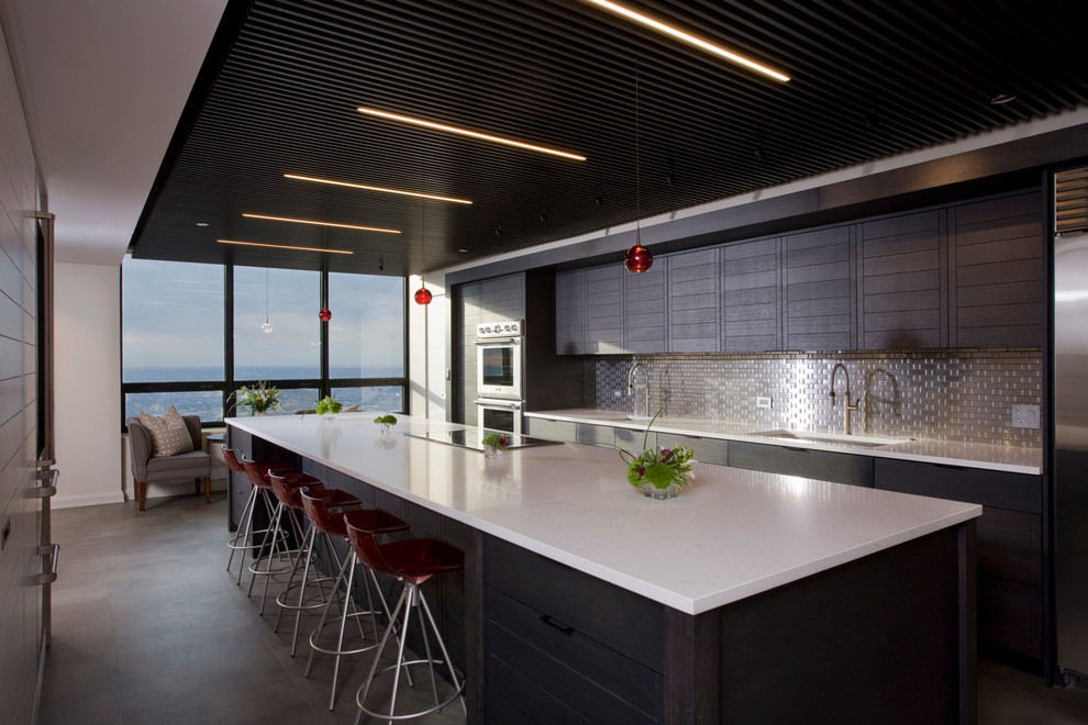 Large contemporary galley open plan kitchen in Chicago with an undermount sink, flat-panel cabinets, dark wood cabinets, quartz benchtops, metallic splashback, metal splashback, stainless steel appliances, laminate floors and with island.