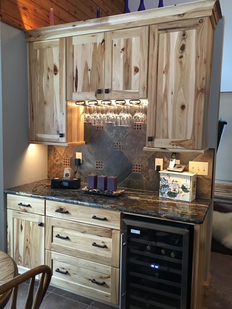 Example of a large mountain style galley porcelain tile and brown floor eat-in kitchen design with a double-bowl sink, shaker cabinets, light wood cabinets, quartzite countertops, gray backsplash, stone slab backsplash, black appliances and an island