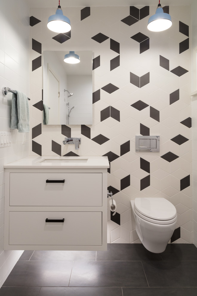 Inspiration for a contemporary bathroom in New York with flat-panel cabinets, white cabinets, a wall-mount toilet, black and white tile, multi-coloured walls, an undermount sink and grey floor.