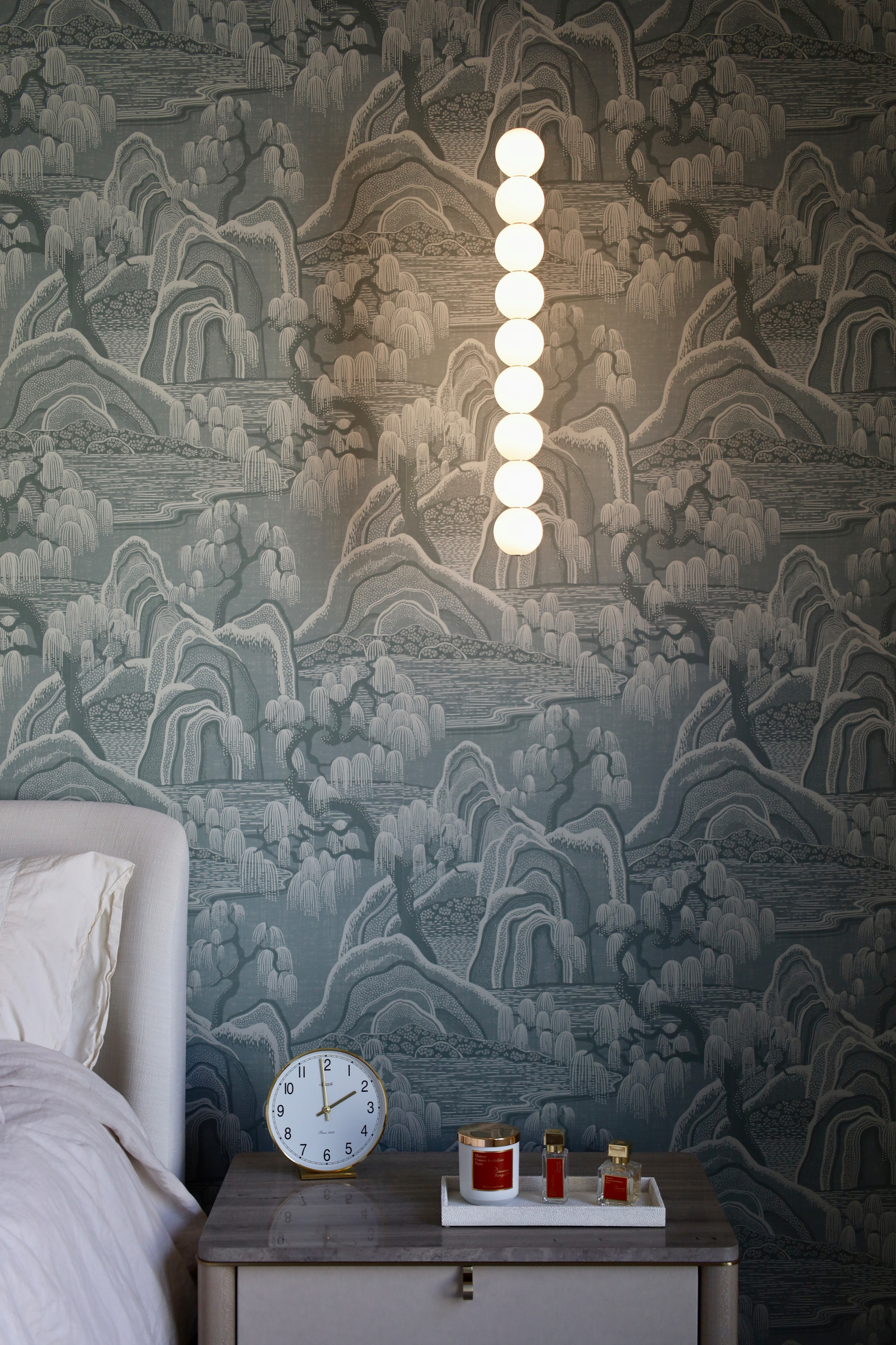 This thoughtfully designed luxury primary bedroom blends refined materials with calming tones to create a serene, elevated retreat. A custom statement wallpaper in soft blue and gray hues adds depth a