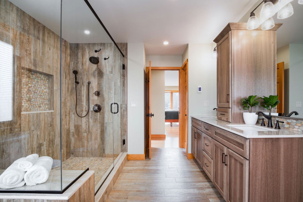 Inspiration for a mid-sized country master bathroom with flat-panel cabinets, light wood cabinets, a double shower, multi-coloured tile, pebble tile, beige walls, an undermount sink, beige floor, a hinged shower door, white benchtops, a shower seat and a double vanity.
