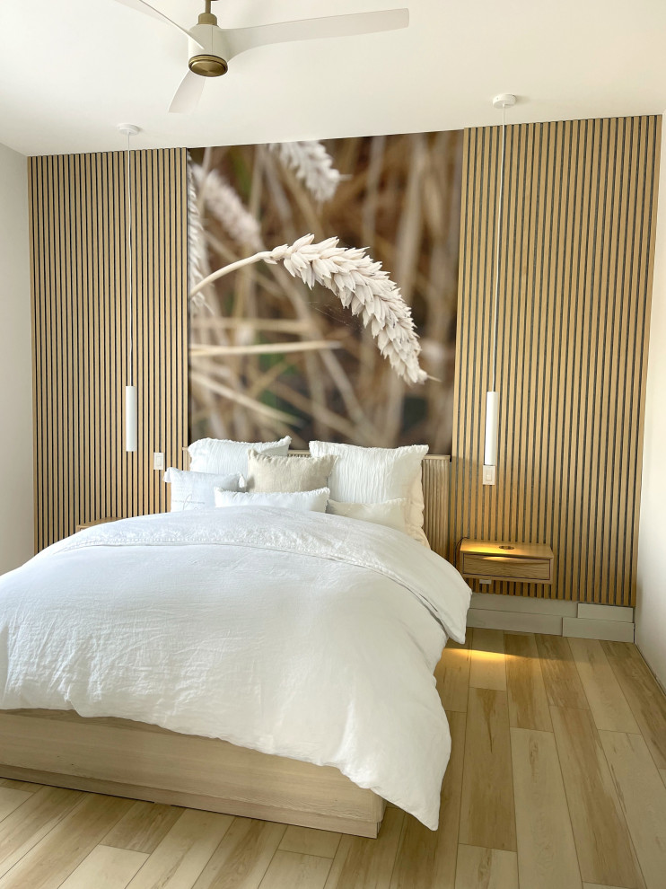 Imagen de dormitorio principal actual de tamaño medio con paredes blancas, suelo de madera clara y panelado