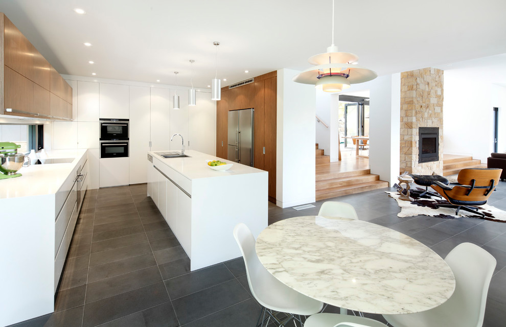 Mid-sized contemporary galley open plan kitchen in Sydney with an undermount sink, flat-panel cabinets, white cabinets, quartzite benchtops, stainless steel appliances, porcelain floors and with island.