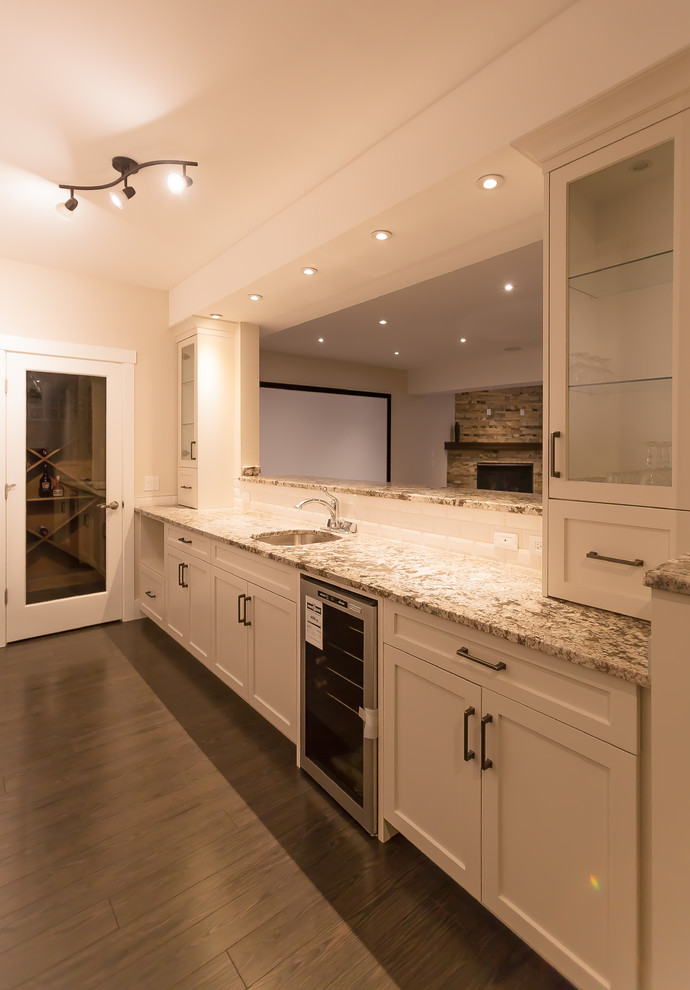 Inspiration for a large transitional u-shaped dark wood floor and brown floor kitchen remodel in Calgary with an undermount sink, shaker cabinets, white cabinets, granite countertops, white backsplash, subway tile backsplash, stainless steel appliances and an island