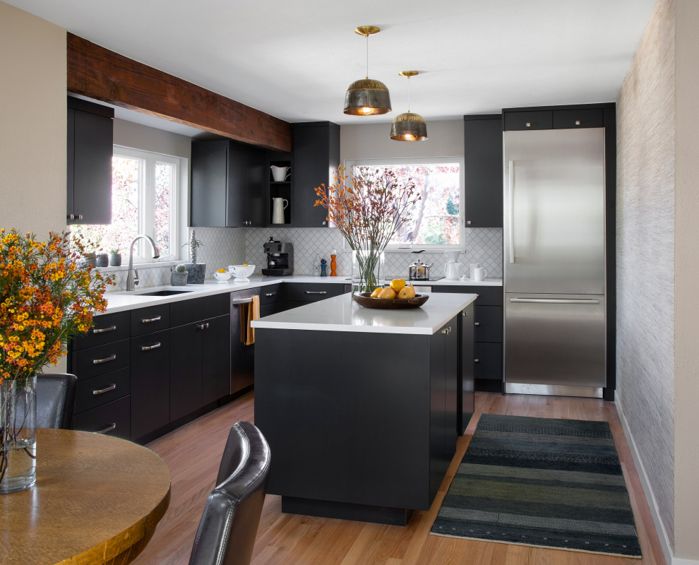 Inspiration for a mid-sized transitional l-shaped eat-in kitchen in Denver with an undermount sink, black cabinets, quartz benchtops, white splashback, stone tile splashback, stainless steel appliances, medium hardwood floors, with island, brown floor and white benchtop.