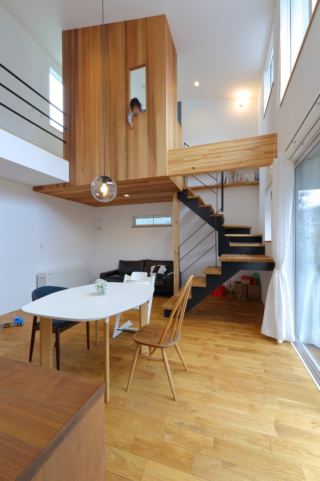 This is an example of a contemporary open plan dining in Tokyo with white walls, light hardwood floors and beige floor.