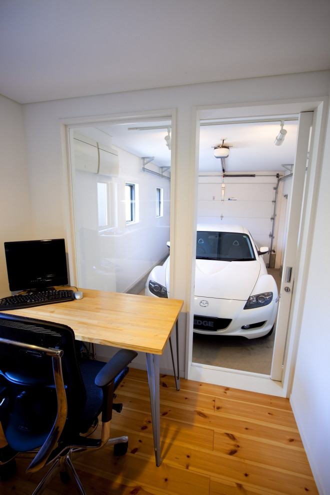 This is an example of a mid-sized study room in Other with white walls, plywood floors, a freestanding desk and brown floor.